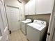 Laundry room with white washer and dryer, white cabinets, and tile floor at 681 Coronado Dr, Kissimmee, FL 34759