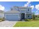 Two-story blue house with a gray roof, front yard, two-car garage and well manicured lawn at 3054 Suraj Cir, Tavares, FL 32778