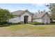 Gray stucco house with tile roof, stone accents, and lush landscaping; inviting front entrance at 25515 Hawks Run Ln, Sorrento, FL 32776