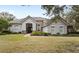 One-story house with gray stucco, stone accents, and a tile roof, showcasing a manicured lawn at 25515 Hawks Run Ln, Sorrento, FL 32776