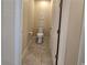 A neutral-toned half bathroom featuring a toilet and a doorway, with ceramic tile floors at 840 Jasmine Creek Rd, Kissimmee, FL 34759
