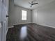 A spacious bedroom with modern dark wood flooring, ceiling fan, and natural light from the window at 840 Jasmine Creek Rd, Kissimmee, FL 34759