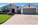 Charming single-story home featuring a brick driveway, manicured lawn, stone accents, and a two-car garage at 840 Jasmine Creek Rd, Kissimmee, FL 34759