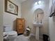 A powder room features a pedestal sink, oak cabinet, round mirror, and floral artwork at 840 Jasmine Creek Rd, Kissimmee, FL 34759