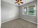Simple carpeted bedroom with a ceiling fan and a window overlooking a green landscape at 3125 Winesap Way, Winter Garden, FL 34787