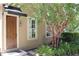 Tan house exterior with a wooden door, landscaping, and a tree at 222 Acadia Ter, Celebration, FL 34747