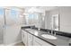 Modern bathroom with double vanity sinks, sleek black countertop, and a glass-enclosed shower at 1231 Teal Creek Dr, St Cloud, FL 34771