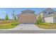 Exterior view of a two-car garage, tan color, and asphalt driveway at 1231 Teal Creek Dr, St Cloud, FL 34771
