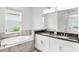 Bright bathroom featuring a double sink vanity and a large soaking tub with natural light at 5267 Stone Ridge Pl, St Cloud, FL 34771