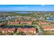 Panoramic view of community featuring terracotta roofs, pond with fountain, mature trees, and nearby highway at 5536 Metrowest Blvd # 8-304, Orlando, FL 32811