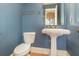 Classic bathroom with pedestal sink, toilet, and decorative blue wallpaper at 5100 Linwood Cir, Sanford, FL 32771