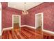 Elegant dining room features decorative wallpaper, chandelier lighting, and gleaming hardwood floors at 5100 Linwood Cir, Sanford, FL 32771