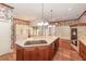 Spacious kitchen boasts a large island with cooktop, granite countertops, wooden cabinetry, and brick fireplace oven at 5100 Linwood Cir, Sanford, FL 32771
