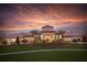 A beautiful exterior elevation of a clubhouse at dusk, framed by a stunning sunset at 1585 Mulligan Blvd, Davenport, FL 33896