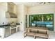 The outdoor kitchen has a granite countertop, stainless steel grill, mini-fridge, storage and exhaust hood at 10193 Brocksport Cir, Gotha, FL 34734
