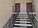 Condo entrance featuring concrete stairs, iron railings, and two brown doors with an outdoor light fixture above the doors at 1181 Paseo Del Mar # D, Casselberry, FL 32707