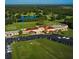 Aerial view of the expansive clubhouse at the golf course with ample parking and lush green surroundings at 3911 Gardenia Dr, Indian Lake Estates, FL 33855