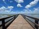 Scenic view of a lake from a wooden pier under a bright, cloudy blue sky at 3911 Gardenia Dr, Indian Lake Estates, FL 33855