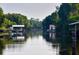 Tranquil view of a waterway lined with lush trees and boathouses on a calm day at 3911 Gardenia Dr, Indian Lake Estates, FL 33855
