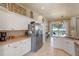 Well-lit kitchen featuring stainless steel refrigerator, white cabinets, and view to outdoor living space at 404 Hightower Dr, Debary, FL 32713