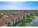 Aerial view of apartments with red tile roofs, landscaping, and a pond in a community at 5530 Metrowest Blvd # 9-211, Orlando, FL 32811
