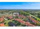 An aerial showcases the community, its beautiful lake with fountain, swimming pool, and manicured lawns under a clear blue sky at 5530 Metrowest Blvd # 9-311, Orlando, FL 32811
