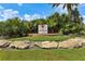 Community entrance sign amidst lush palms, creating a welcoming and tropical atmosphere for residents and guests at 5530 Metrowest Blvd # 9-311, Orlando, FL 32811