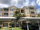Beige condo building with screened balconies, palm trees, and carport parking at 6451 Old Park Ln # 110, Orlando, FL 32835
