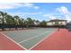 Well-maintained tennis court surrounded by palm trees and a privacy fence at 7642 Fairgrove Ave, Windermere, FL 34786
