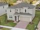 Aerial view of a two-story tan home with a brick driveway, two-car garage, and well-kept lawn at 1197 Happy Forest Loop, Deland, FL 32720