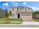Two-story home featuring a tan exterior, two-car garage, a manicured lawn, and sidewalk at 1197 Happy Forest Loop, Deland, FL 32720