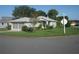Single-story house with gray siding, attached garage, and a grassy yard on a corner lot at 20505 Queen Alexandra Dr, Leesburg, FL 34748