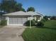 Ranch-style home with gray siding, double garage, and landscaped front yard at 20505 Queen Alexandra Dr, Leesburg, FL 34748