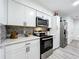 Bright kitchen featuring stainless appliances, gray subway tile backsplash, white cabinets, and wood-look flooring at 4316 Natchez Trace Dr, St Cloud, FL 34769