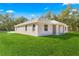 Rear exterior view of home with a cozy covered patio overlooking a sprawling green lawn at 13455 Sw 85 Pl, Dunnellon, FL 34432