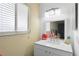 Bright bathroom featuring a white vanity with a sleek countertop, modern lighting fixture, and a window at 2495 Sedgefield Ave, Deltona, FL 32725