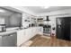 Bright kitchen featuring white cabinets, open shelving, modern appliances, and wood-look flooring at 2495 Sedgefield Ave, Deltona, FL 32725