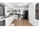 Well-lit kitchen with white cabinetry, stainless steel appliances, open shelving, and wood-style flooring at 2495 Sedgefield Ave, Deltona, FL 32725