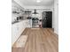 Well-lit kitchen with white cabinetry, stainless steel appliances, open shelving, and wood-look flooring at 2495 Sedgefield Ave, Deltona, FL 32725