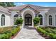 Elegant front entrance featuring a tiled walkway, double doors, lush landscaping, and a stylish arched entryway at 1306 Sweetwater Club Blvd, Longwood, FL 32779