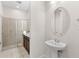 Small bathroom with pedestal sink, oval mirror, and shower at 154 Captiva Dr, Davenport, FL 33896