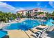 Large community pool with plenty of lounge chairs and umbrellas surrounded by palm trees and apartments in the background at 4114 Breakview Dr # 406, Orlando, FL 32819