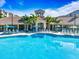 Resort-style pool with umbrellas and lounge chairs in front of a clubhouse with arched entrance and palm trees at 4114 Breakview Dr # 406, Orlando, FL 32819