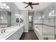 Bright bathroom featuring double sinks, soaking tub and walk-in shower with neutral tile work and dark wood floors at 290 Silver Maple Rd, Groveland, FL 34736