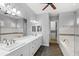 Bright bathroom featuring double sinks, soaking tub and walk-in shower with neutral tile work and dark wood floors at 290 Silver Maple Rd, Groveland, FL 34736