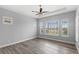 This primary bedroom has wood floors, many windows with wood shutters, and a trey ceiling with ceiling fan at 290 Silver Maple Rd, Groveland, FL 34736