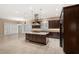 This kitchen has tile floors, dark cabinets, granite counters, an island with seating, and stainless steel appliances at 290 Silver Maple Rd, Groveland, FL 34736