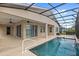 A backyard pool is surrounded by a screened-in enclosure, grass, a home, and an outdoor kitchen at 290 Silver Maple Rd, Groveland, FL 34736