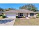 Single-story house with a white garage door and landscaped lawn at 4490 Treasure Cay Rd, Tavares, FL 32778