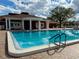 Inviting community pool with clear blue water, blue steps, lounge chairs, brick pavers and clubhouse at 4901 Pleasant Hollow Trl, Lakeland, FL 33811